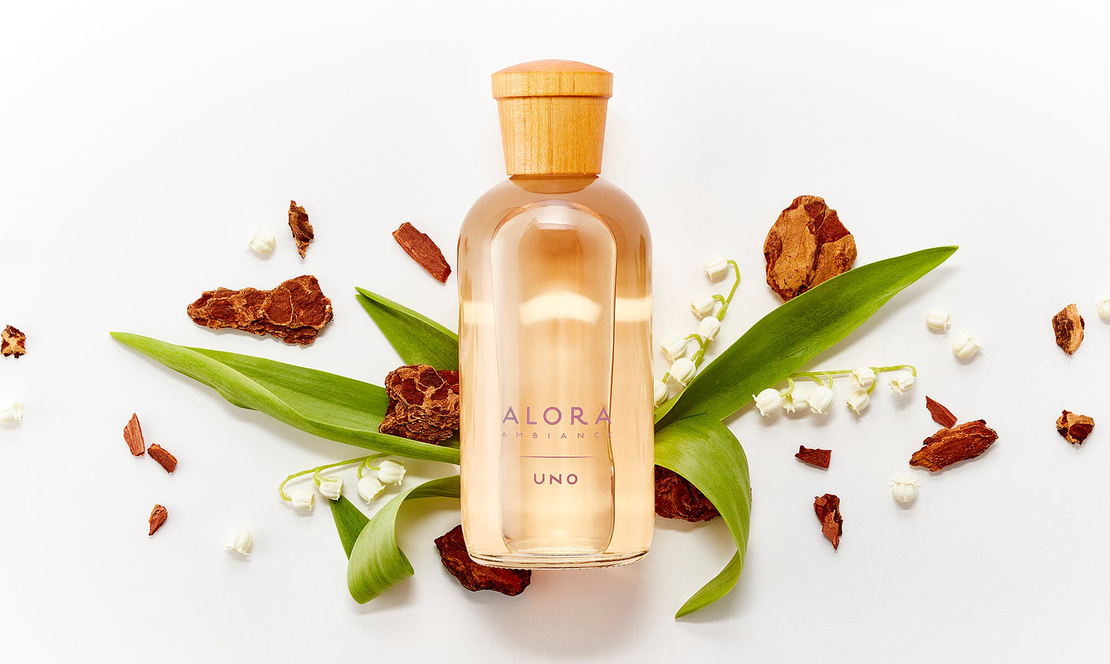 Uno diffuser bottle next to lily of the valley flowers and pieces of sandalwood