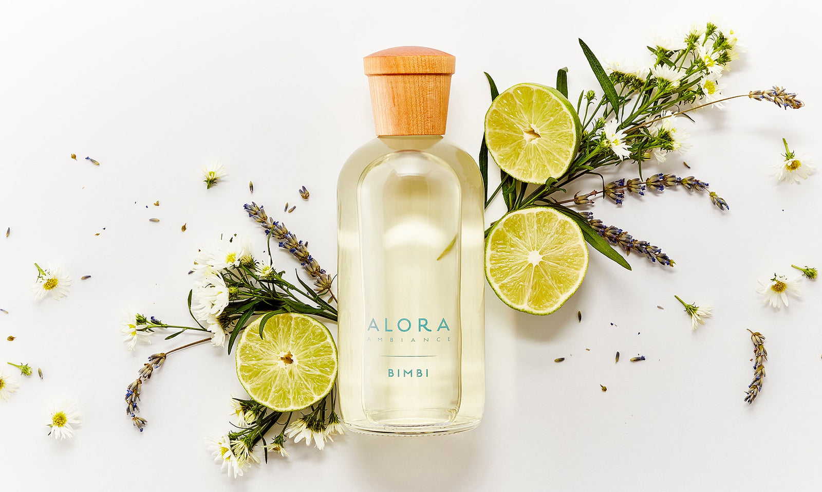 Bimbi diffuser bottle next to bergamot halves and fresh chamomile and lavender sprigs