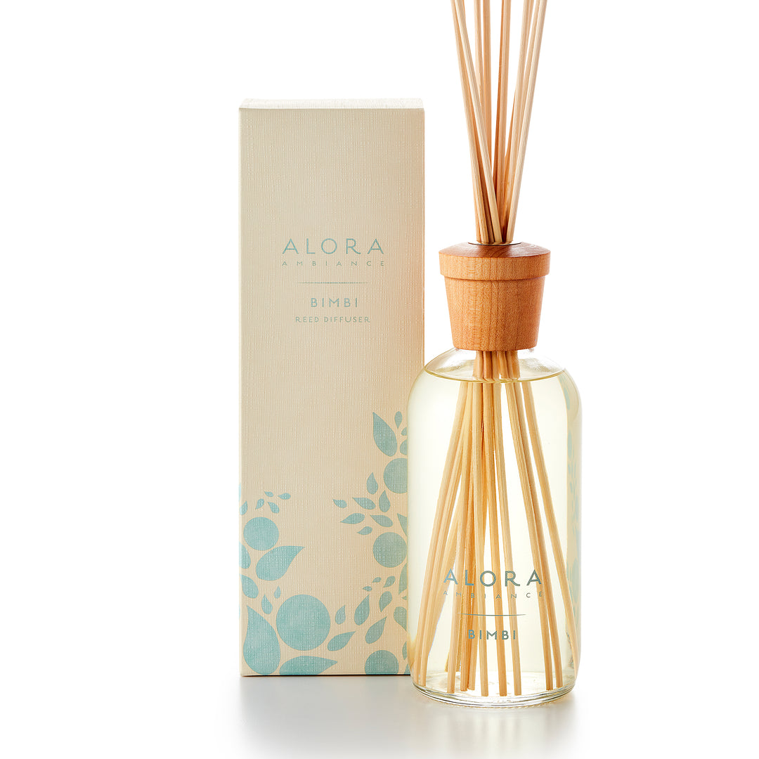 Alora Ambiance 16oz Bimbi reed diffuser with glass bottle and wooden cap next to tan box with baby blue floral pattern on it.