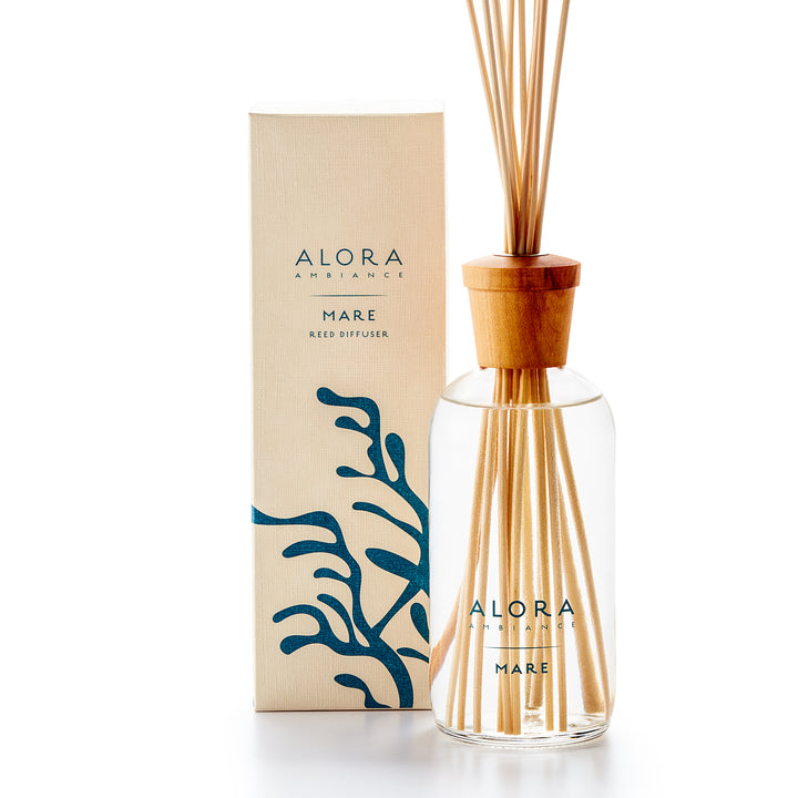 Alora Ambiance 16oz Mare reed diffuser with glass bottle and wooden cap next to tan box with blue kelp pattern on it.