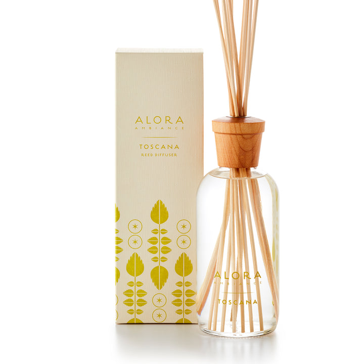 Alora Ambiance 16oz Toscana reed diffuser with glass bottle and wooden cap next to tan box with pea green leaf pattern on it.