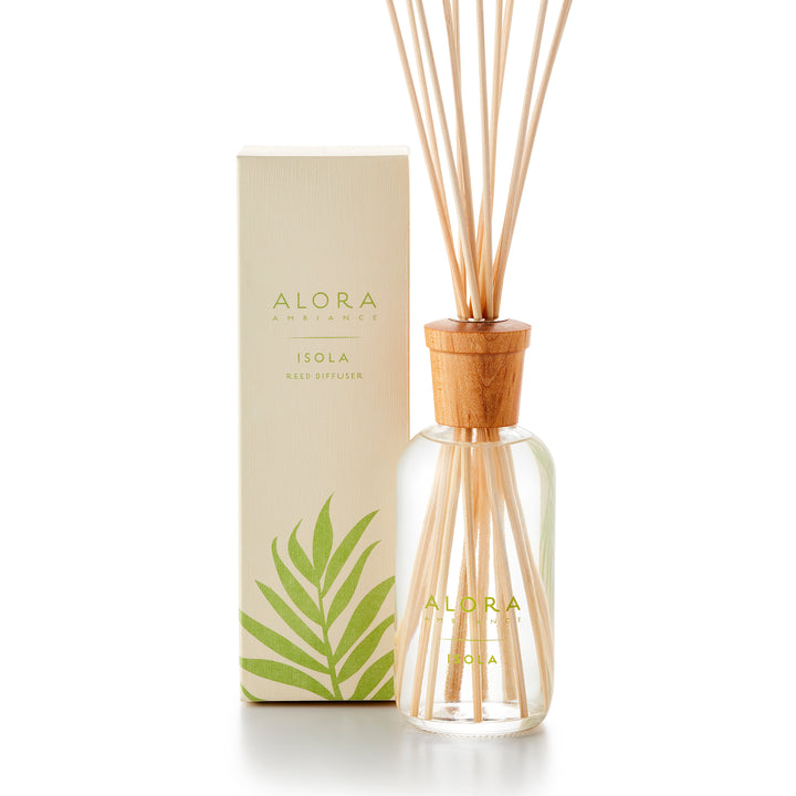 Alora Ambiance 8oz Isola reed diffuser with glass bottle and wooden cap next to tan box with green tropical leaf pattern on it.