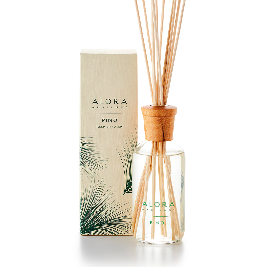 Alora Ambiance 8oz Pino reed diffuser with glass bottle and wooden cap next to tan box with green pine needle pattern on it.
