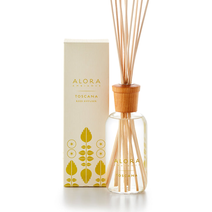 Alora Ambiance 8oz Toscana reed diffuser with glass bottle and wooden cap next to tan box with pea green leaf pattern on it.