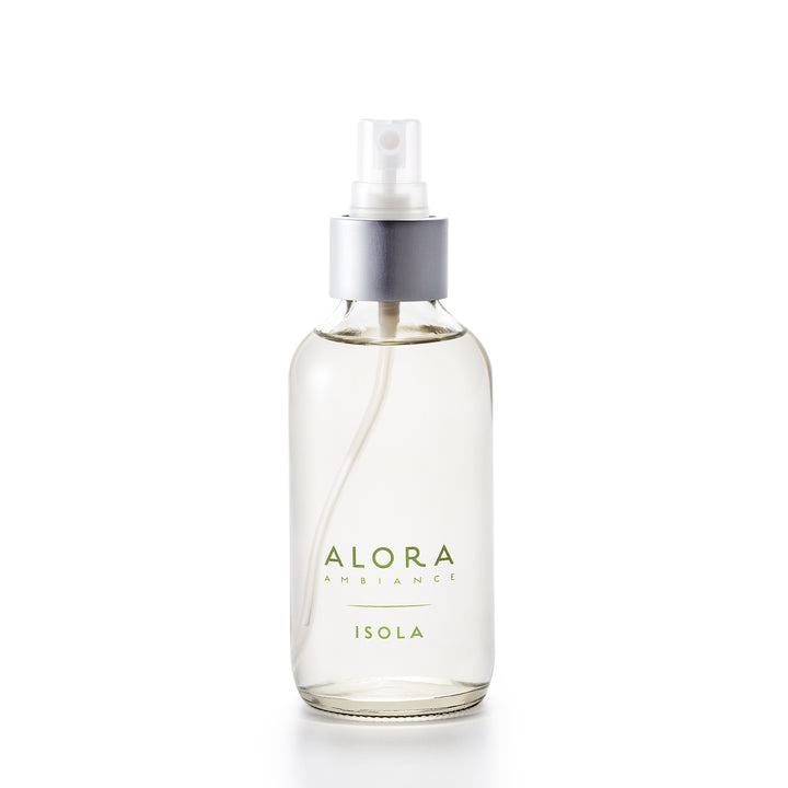 Small, glass spray bottle with "Alora Ambiance" and "Isola" written in green font on the front, bottle is filled with clear liquid fragrance