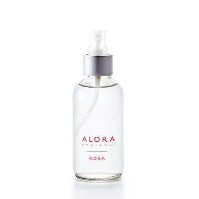 Small, glass spray bottle filled with clear liquid, bottle has the words "Alora Ambiance" and "Rosa" written on the front in pink font