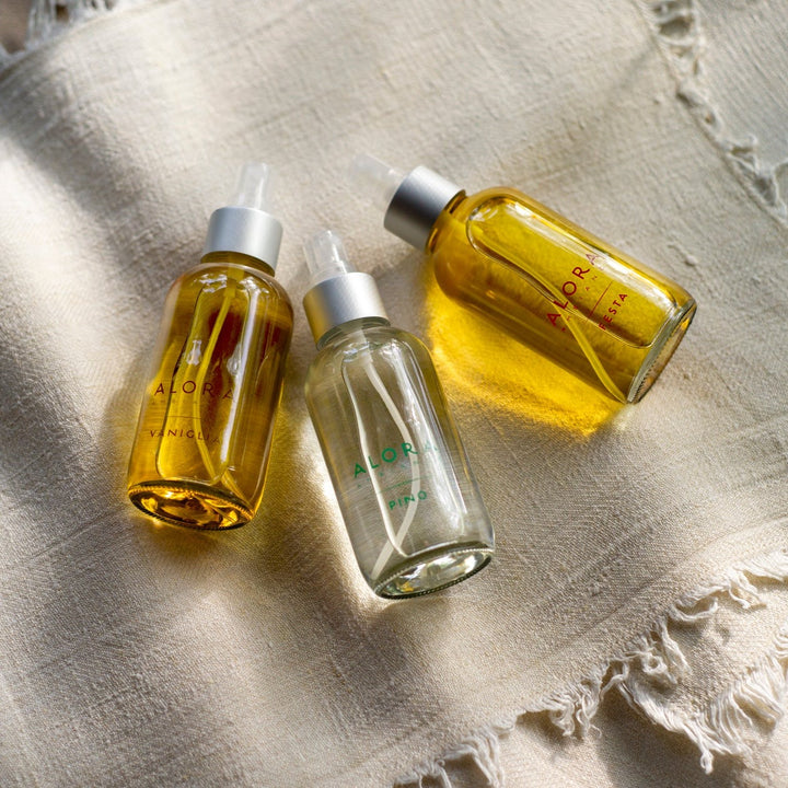 Vaniglia, Pino and Festa scented room sprays laying on a cream linen cloth