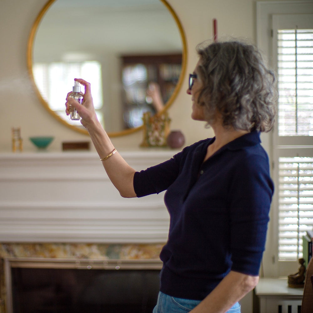 Woman spraying room spray in living room