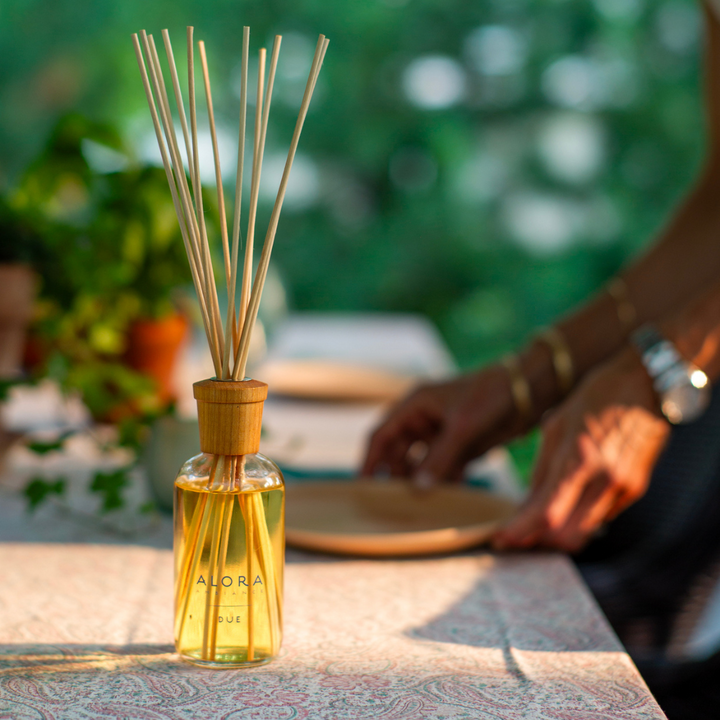 Woman setting a table outside with a Due reed diffuser sitting nearby