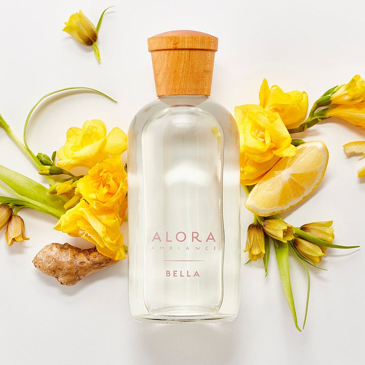 Bella diffuser bottle by ylang ylang flowers, lemon slices, and pieces of ginger