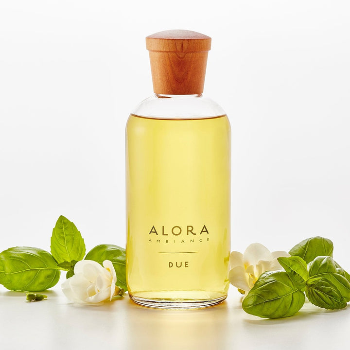 Due diffuser bottle next to fresh basil leaves and jasmine flowers