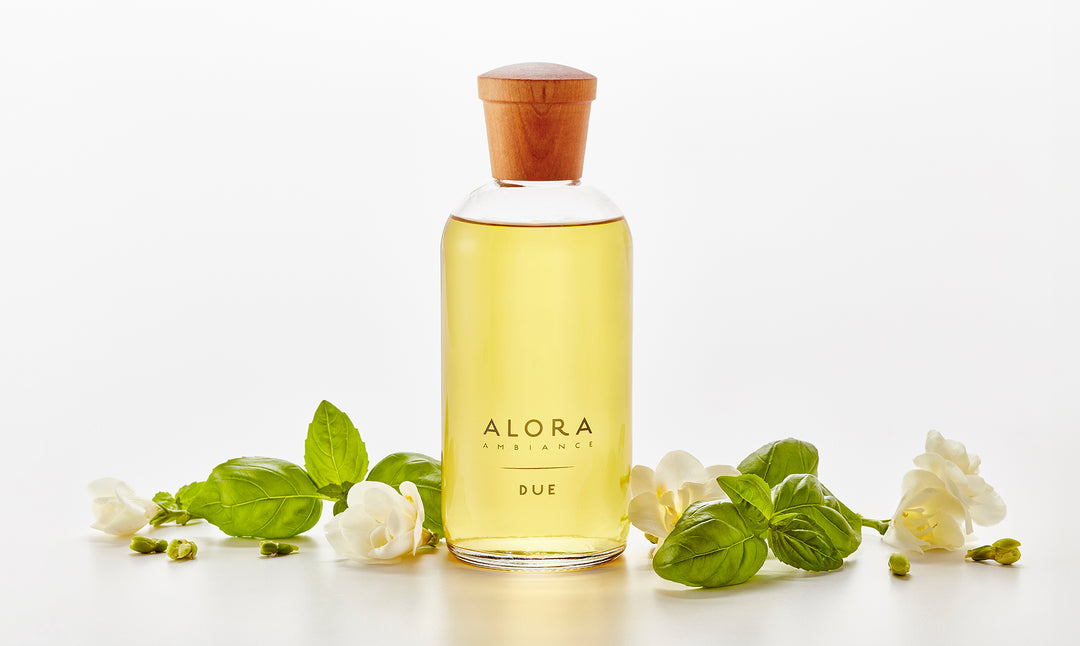 Due diffuser bottle next to fresh basil leaves and jasmine flowers