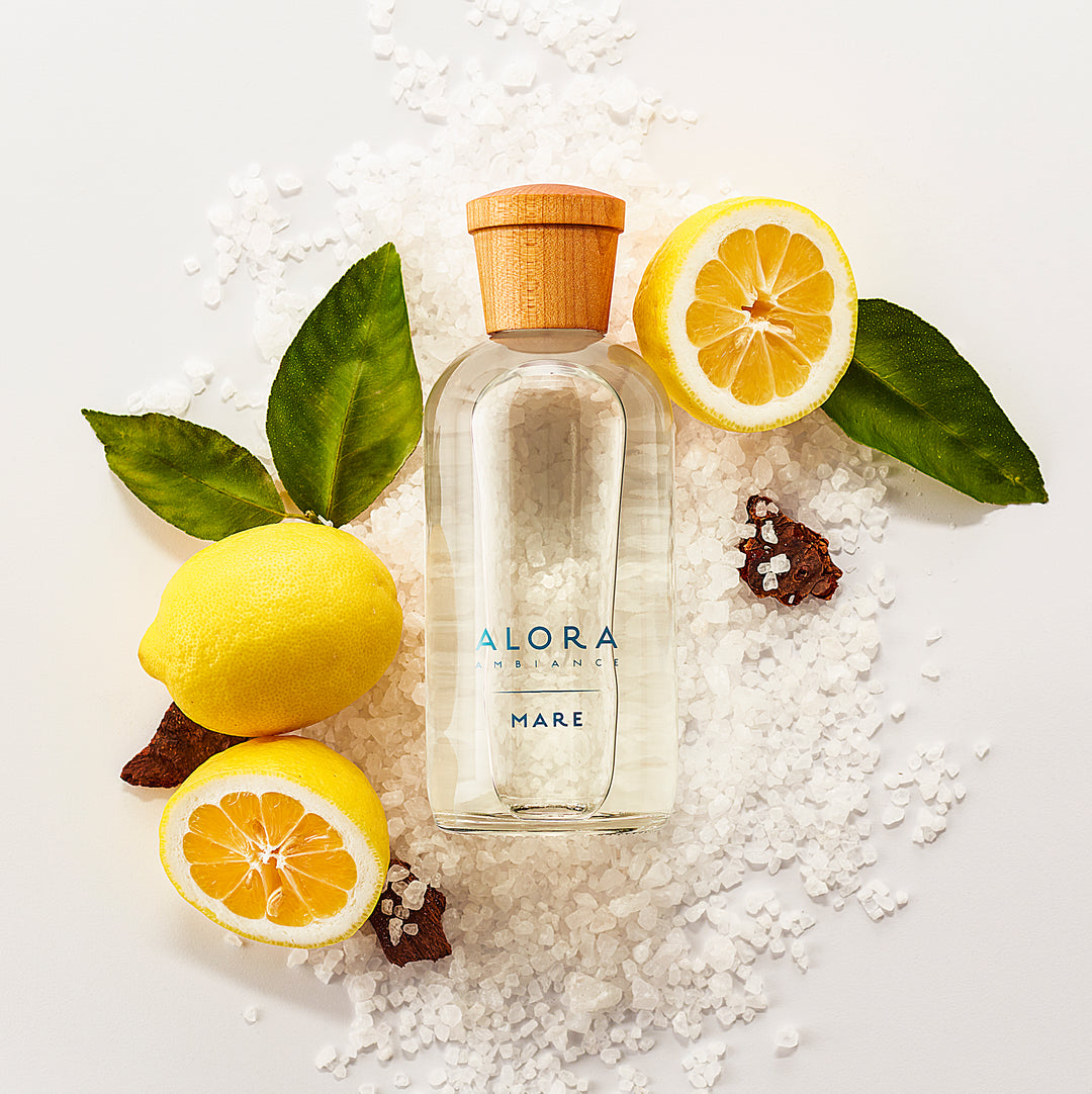 Mare reed diffuser bottle surrounded by lemons, pieces of cedarwood, and sea salt