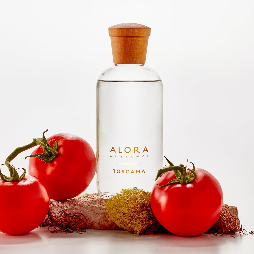 Toscana diffuser bottle sitting on a stone next to tomatoes and green moss