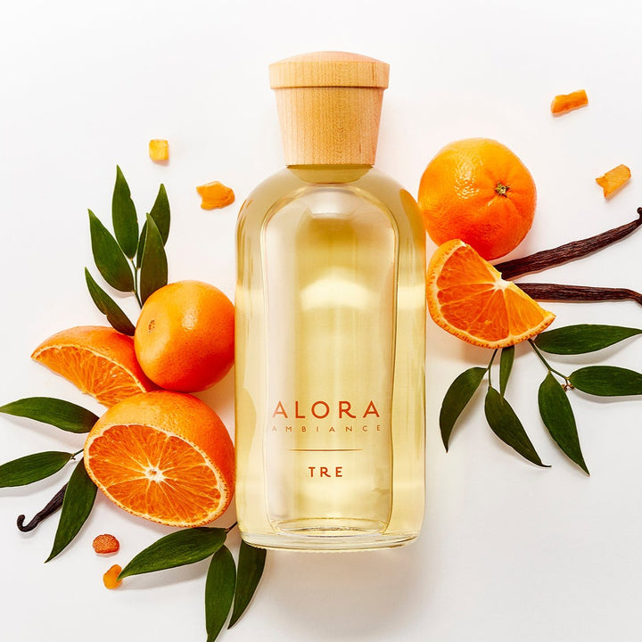 Tre diffuser bottle surrounded by mandarin oranges, vanilla beans, and amber pieces