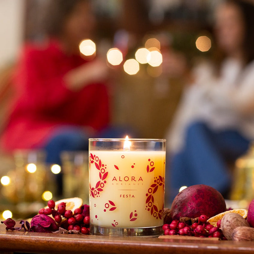 Festa candle burning on coffee table while two people chat in the background