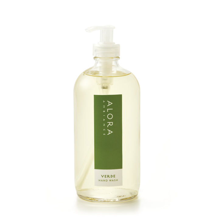 Tall glass bottle topped with a plastic pump and filled with clear, liquid hand wash with label that says “Alora Ambiance” and “Verde Hand Wash” on the front