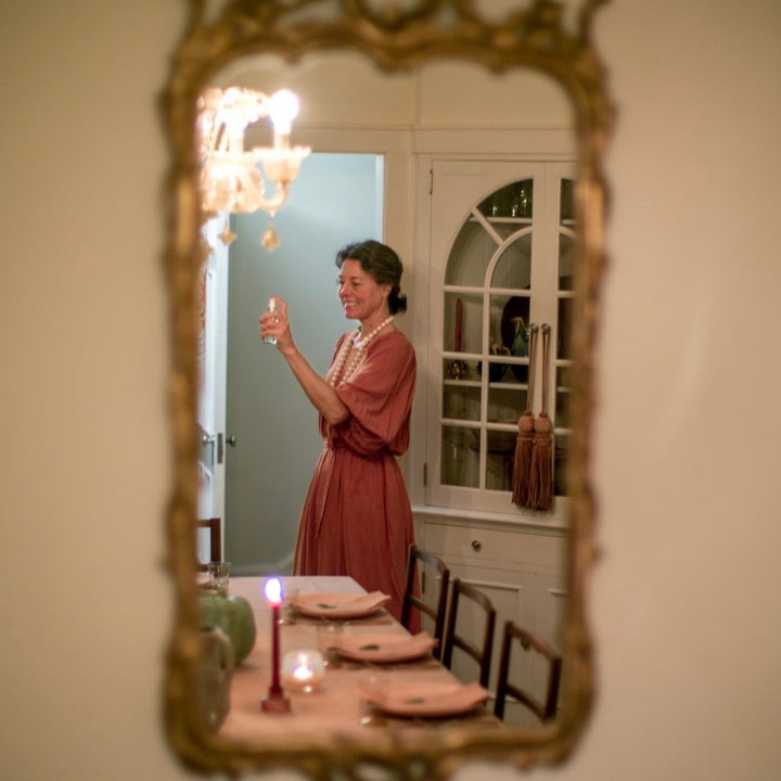 Woman in front of a set dinner table spritzing a room spray