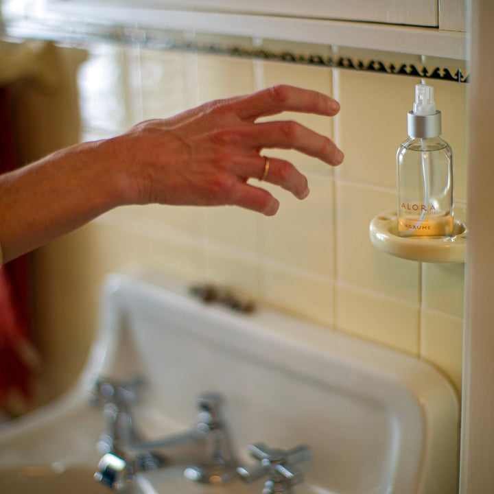 Hand reaching for Agrume room spray in bathroom