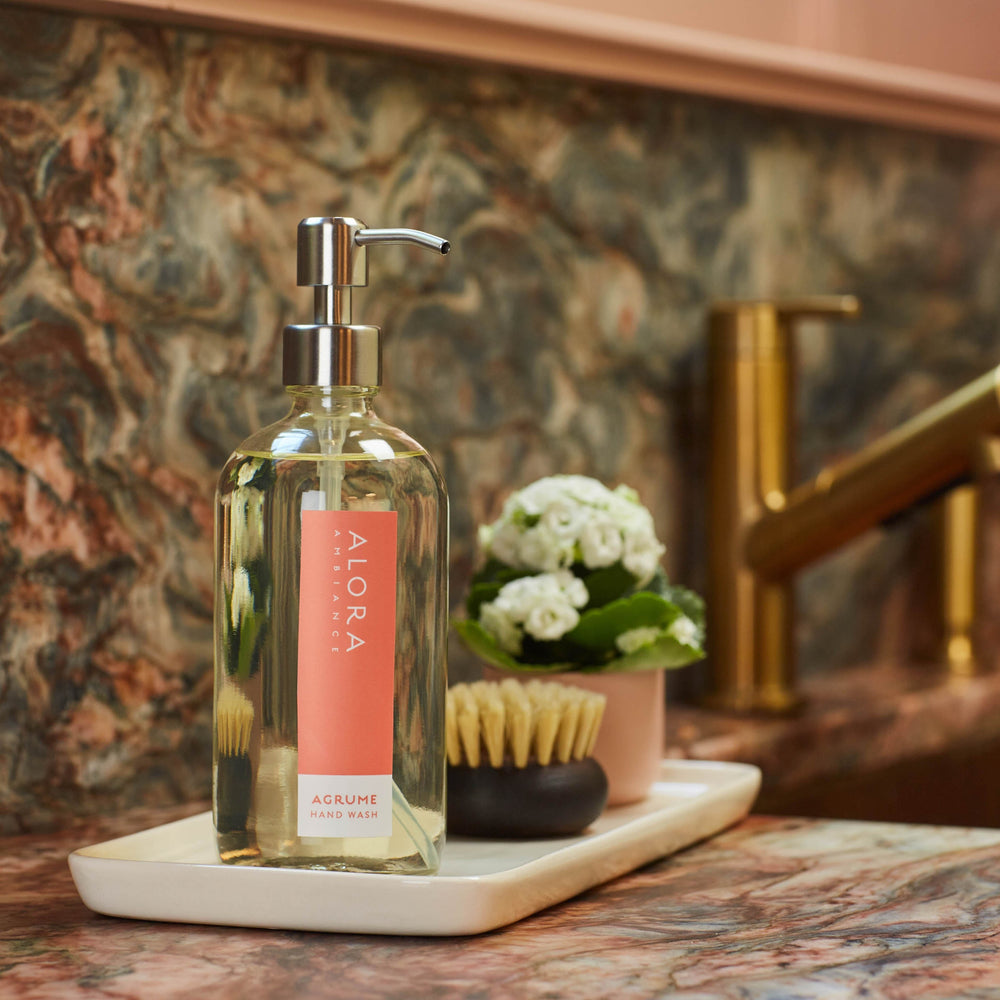 Agrume hand wash bottle on a tray on a kitchen counter next to sink.