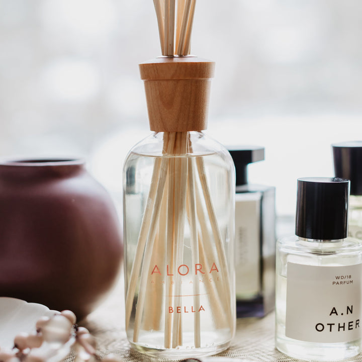 Bella reed diffuser sitting next to various perfume samples