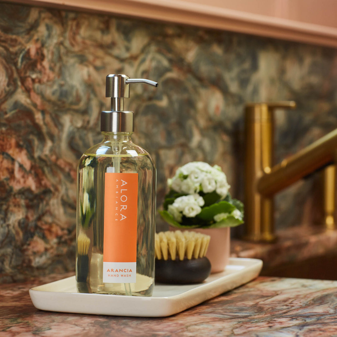 Arancia hand wash bottle on a tray on a kitchen counter next to sink.