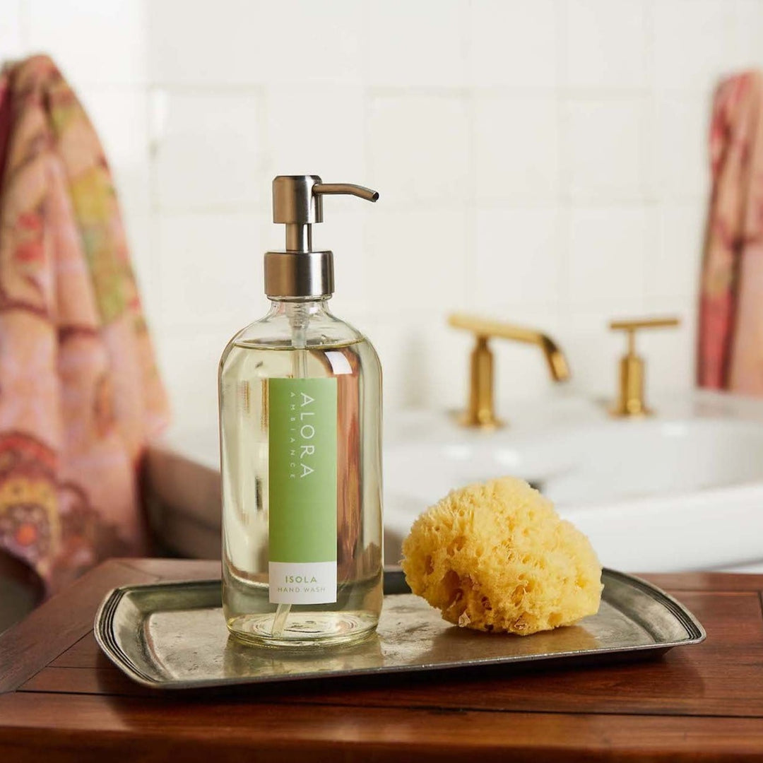 Isola hand wash bottle in a bathroom on a silver tray by a yellow sponge.