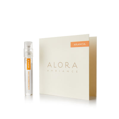 Small clear plastic vial that says “Alora Ambiance” and “Arancia” next to a tan card that also says “Alora Ambiance" and “Arancia”