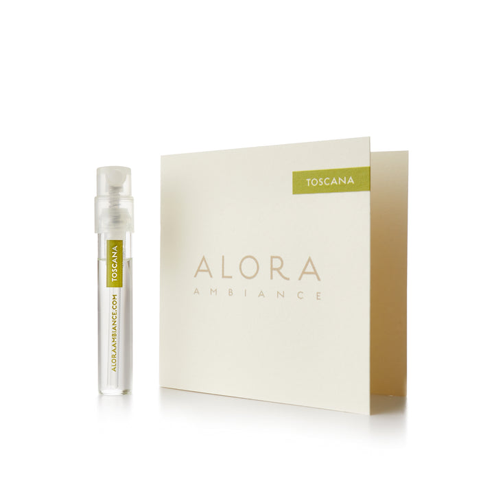 Small clear plastic vial that says “Alora Ambiance” and “Toscana” next to a tan card that also says “Alora Ambiance" and “Toscana”