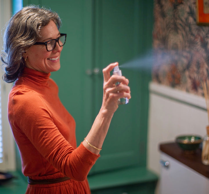 Woman spritzing room spray in a bathroom