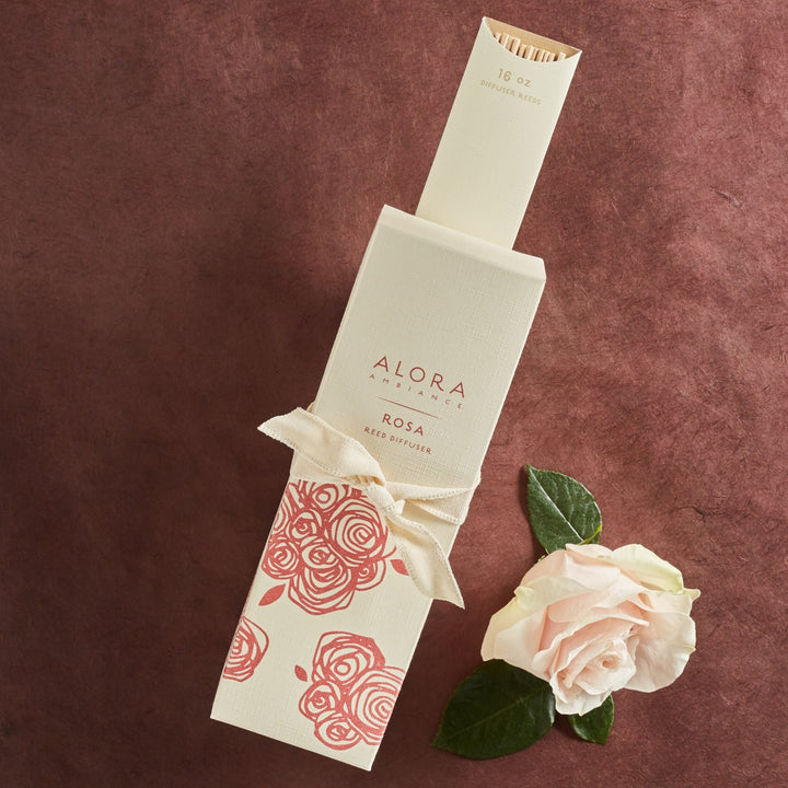 Tall tan box that says "Alora Ambiance" and "Rosa Reed Diffuser" wrapped up with packet of reeds with a tan ribbon