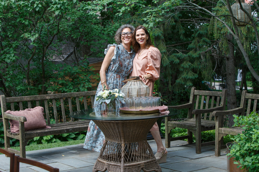 Two woman in dresses smiling in a backyard