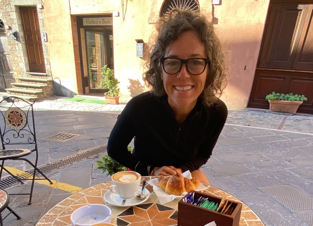 Woman smiling over a capaccino and croissant