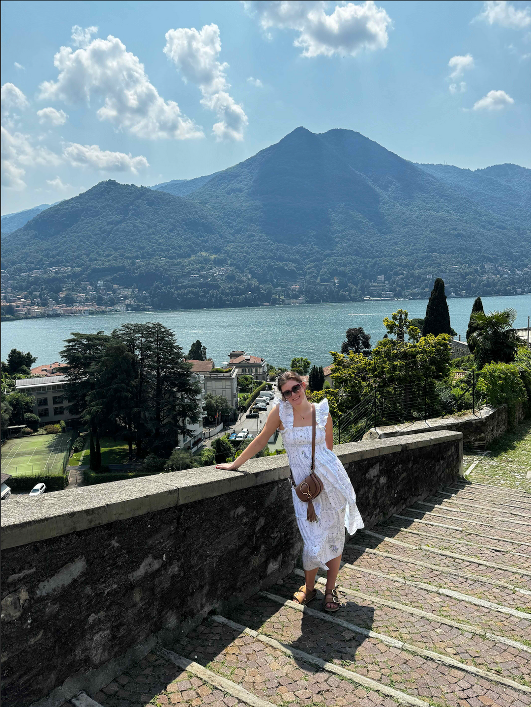 Girl in white sundress standing in front of Lake Como