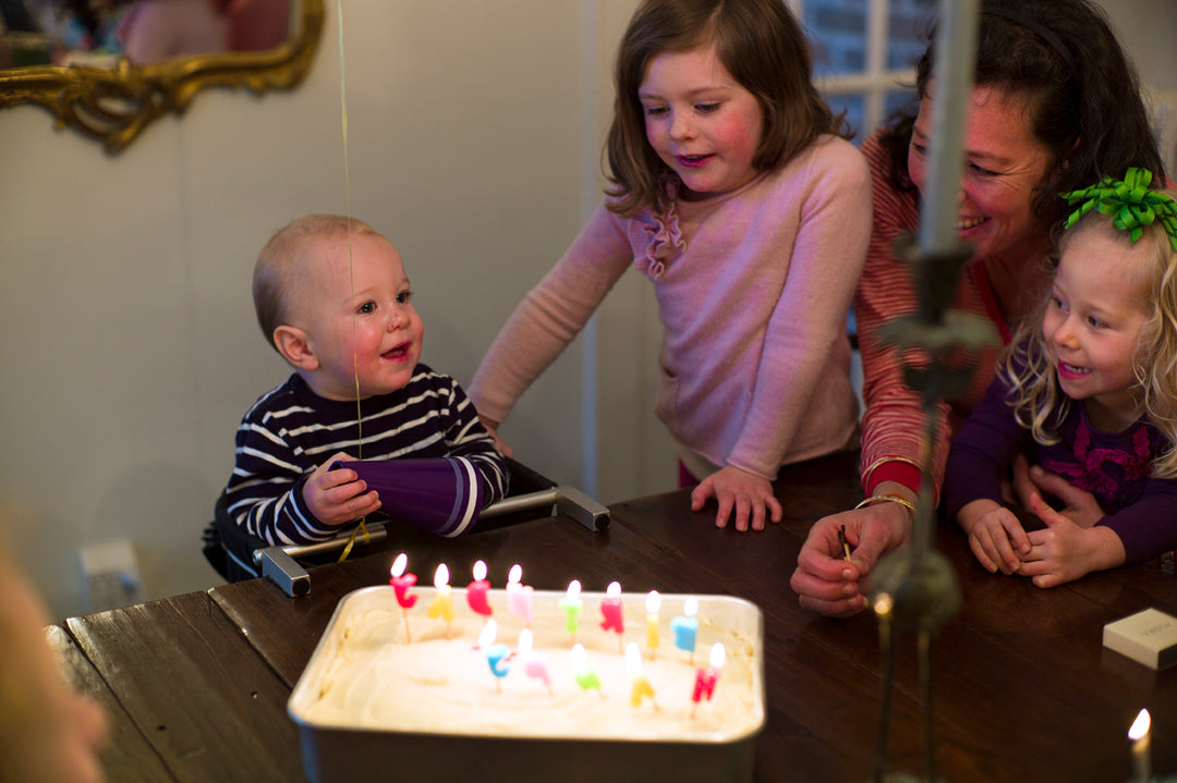 Baby boy sitting by a birthday cake with lit candles