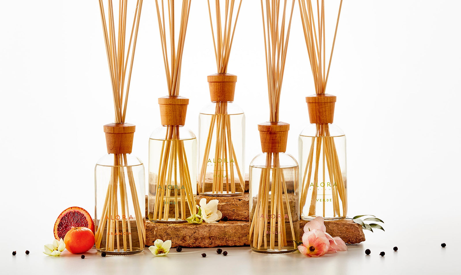 Collection of 7 reed diffusers with various flowers arranged around them.