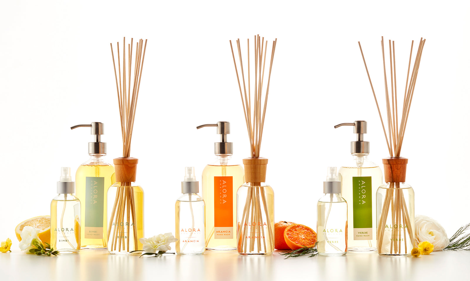 three reed diffusers, three hand washes and three room sprays bundled together with fruit and floral props