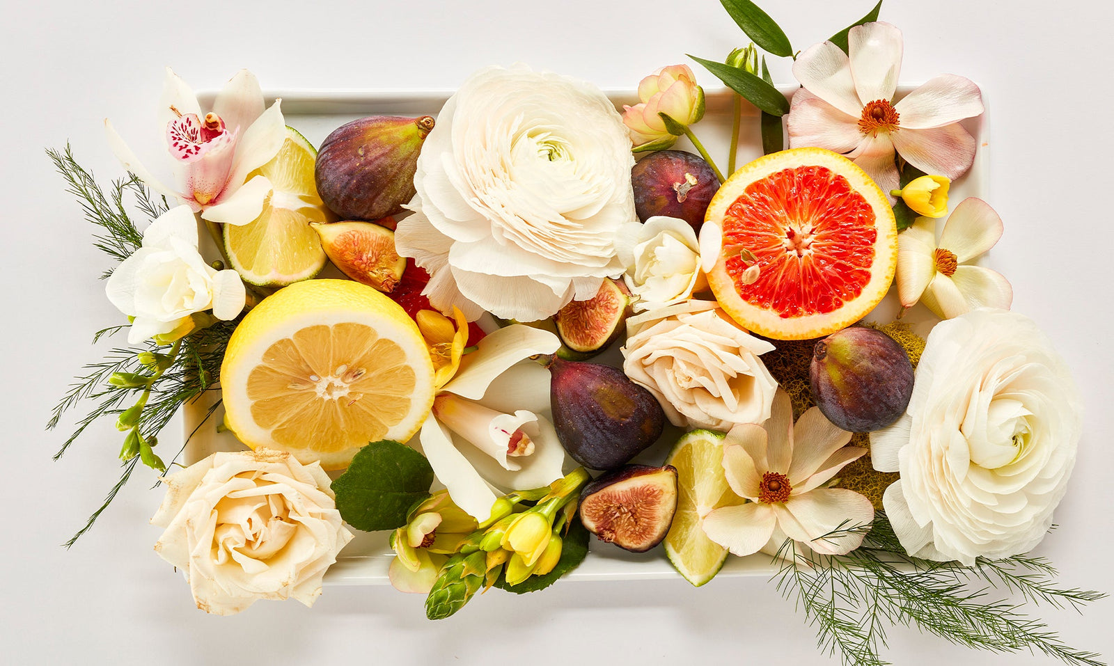 Citrus fruit, fresh flowers, figs and greenery bundled in a box