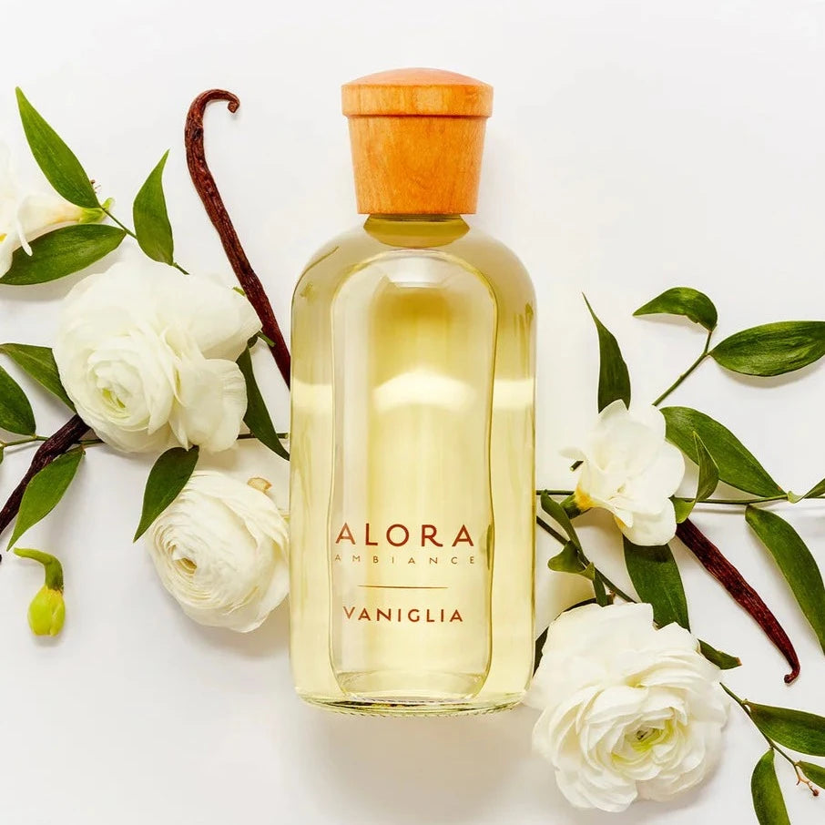 Vaniglia diffuser bottle next to jasmine flowers and vanilla bean pods