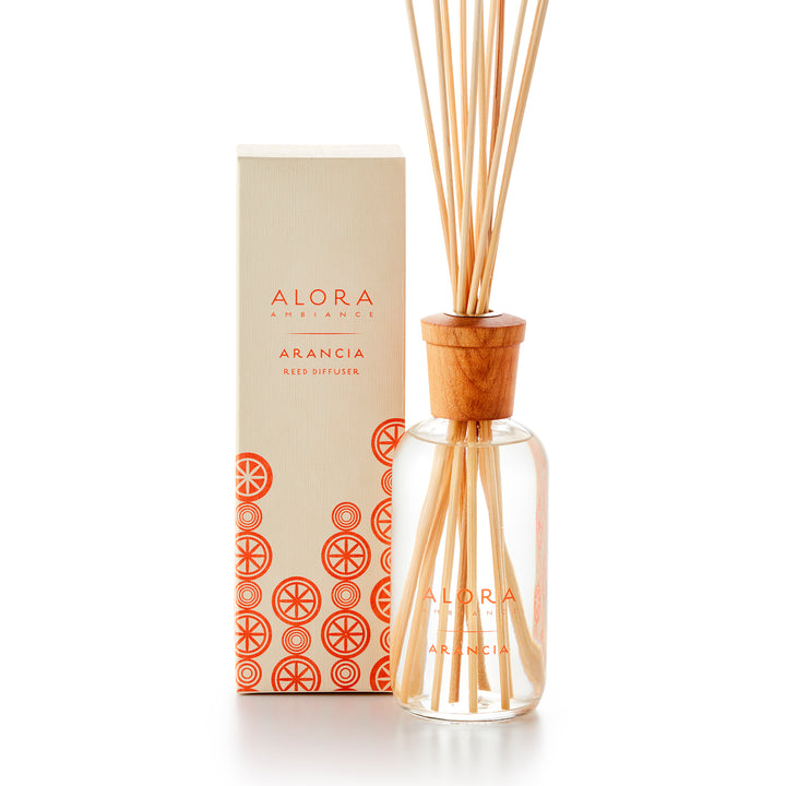 Alora Ambiance 8oz Arancia reed diffuser with glass bottle and wooden cap next to tan box with pattern of oranges on it.