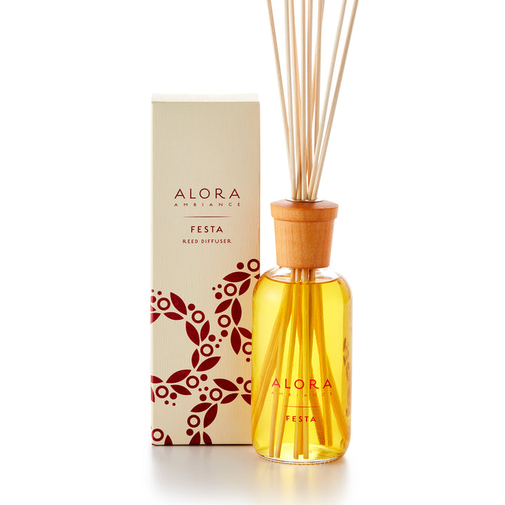 Alora Ambiance 8oz Festa reed diffuser with glass bottle and wooden cap next to tan box with red wreath pattern on it.