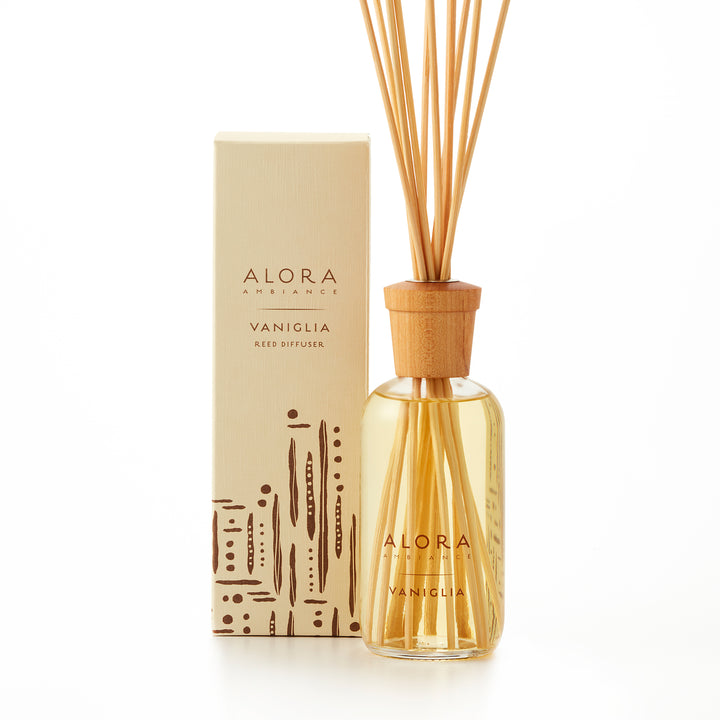 Alora Ambiance 8oz Vaniglia reed diffuser with glass bottle and wooden cap next to tan box with a brown striped and dotted pattern on it.