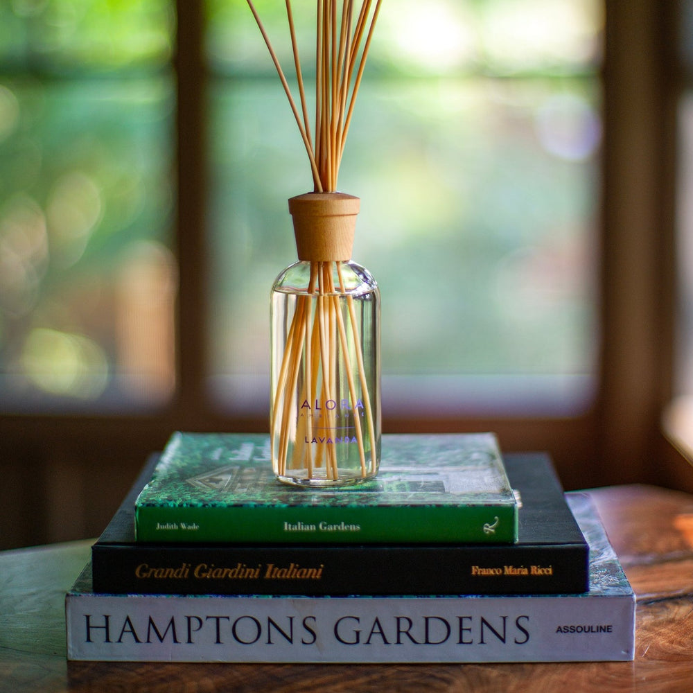 Lavanda reed diffuser on top of a stack of 3 garden books placed in a sunroom