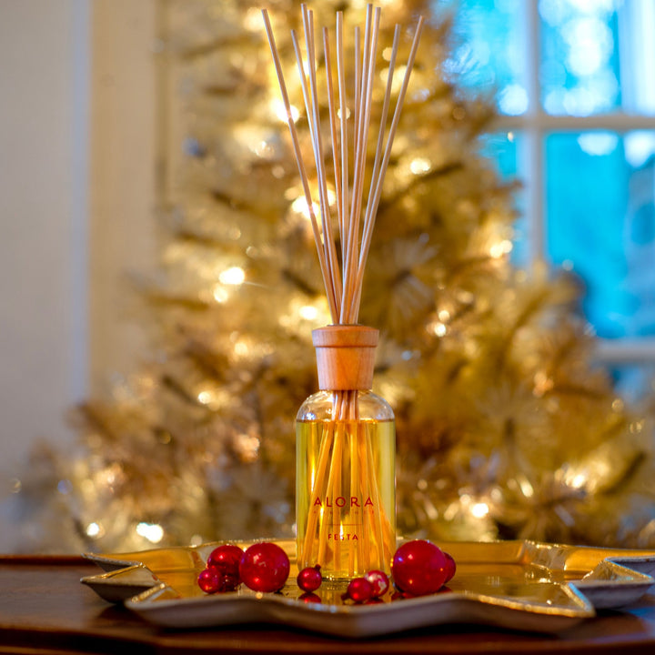 Festa reed diffuser in front of a gold vintage tinsel tree