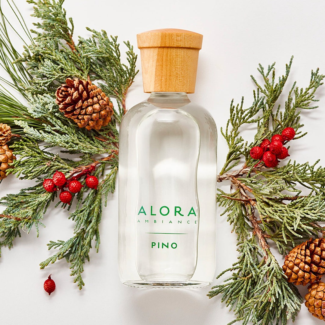 Pino diffuser bottle by pine greens, pine cones, and red berries