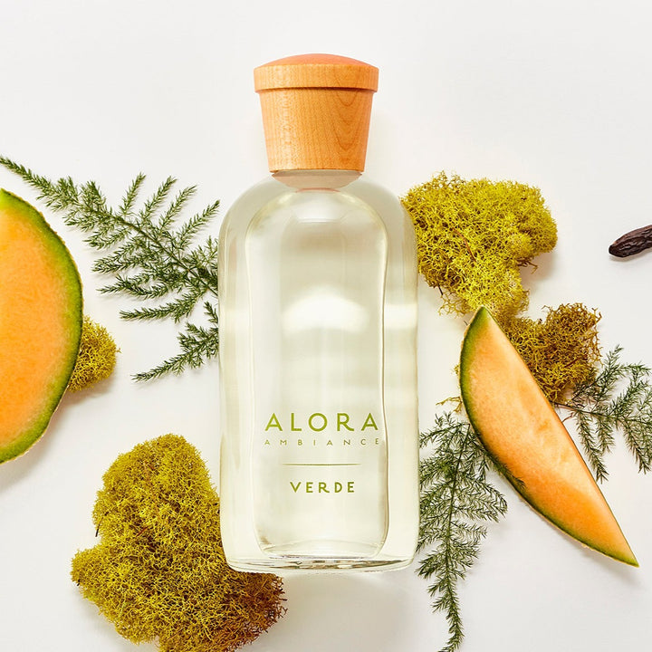 Verde diffuser bottle next to moss, pine greens and cantaloupe slices