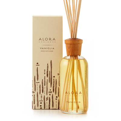 Glass bottle filled with clear, liquid fragrance, topped with wood cap with reeds passing through cap into liquid. Bottle says “Alora Ambiance” and “Vaniglia” and is by a tan box 
