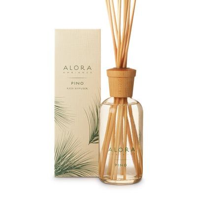 Glass bottle filled with clear, liquid fragrance, topped with wood cap with reeds passing through cap into liquid. Bottle says “Alora Ambiance” and “Pino” and is next to tan box