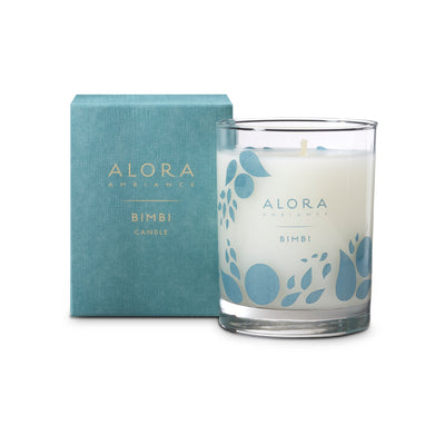White-colored candle in glass jar that says “Alora Ambiance” and “Bimbi” and is next to a blue box that says “Alora Ambiance” and “Bimbi candle”
