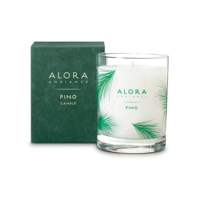 Cream-colored candle in glass jar that says “Alora Ambiance” and “Pino” and is next to a green box that says “Alora Ambiance” and “Pino candle”